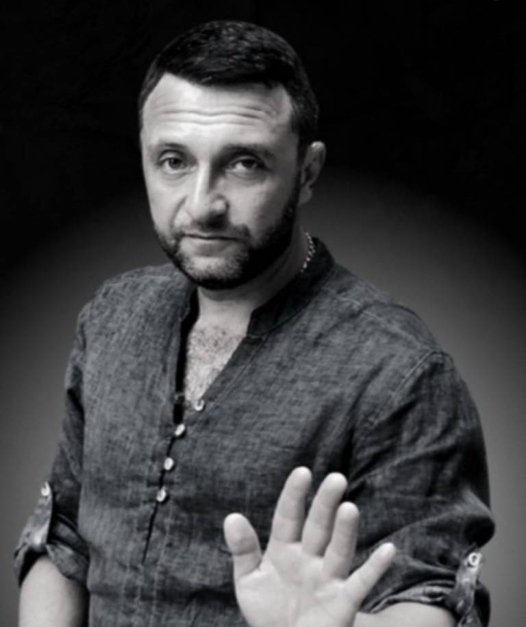 Чорно-білий портрет чоловіка з піднятою долонею у жесті стоп.