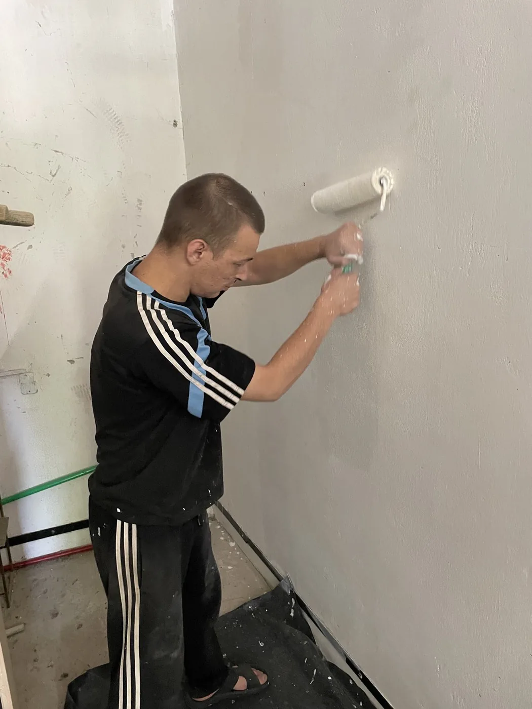 Учасник програми фарбує стіну валиком
