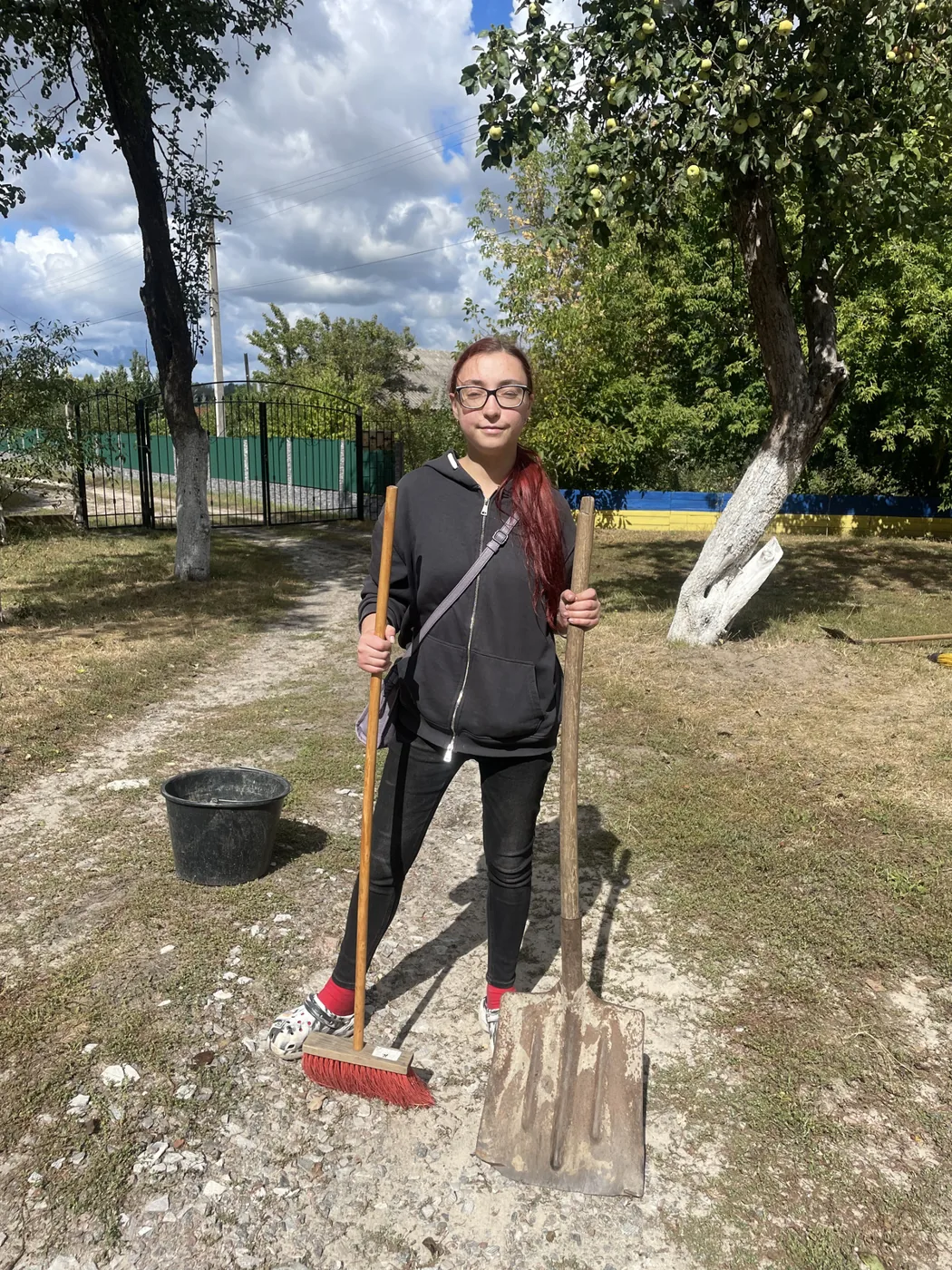 Галя з мітлою та лопатою на подвірʼї центру