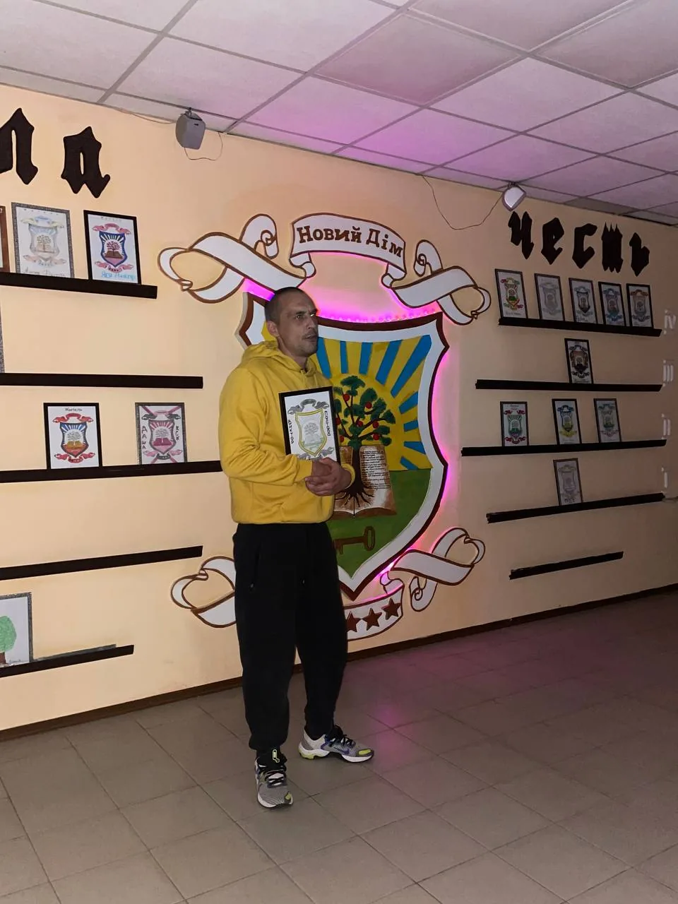 Учасник програми в жовтій футболці з грамотою біля герба «Новий Дім»