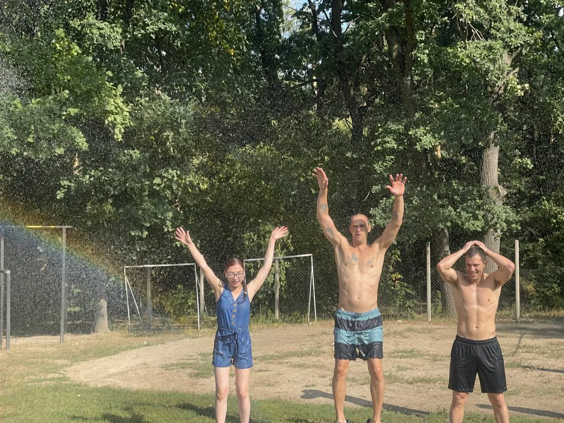 Учасники програми з піднятими руками на галявині біля центру в останні теплі дні