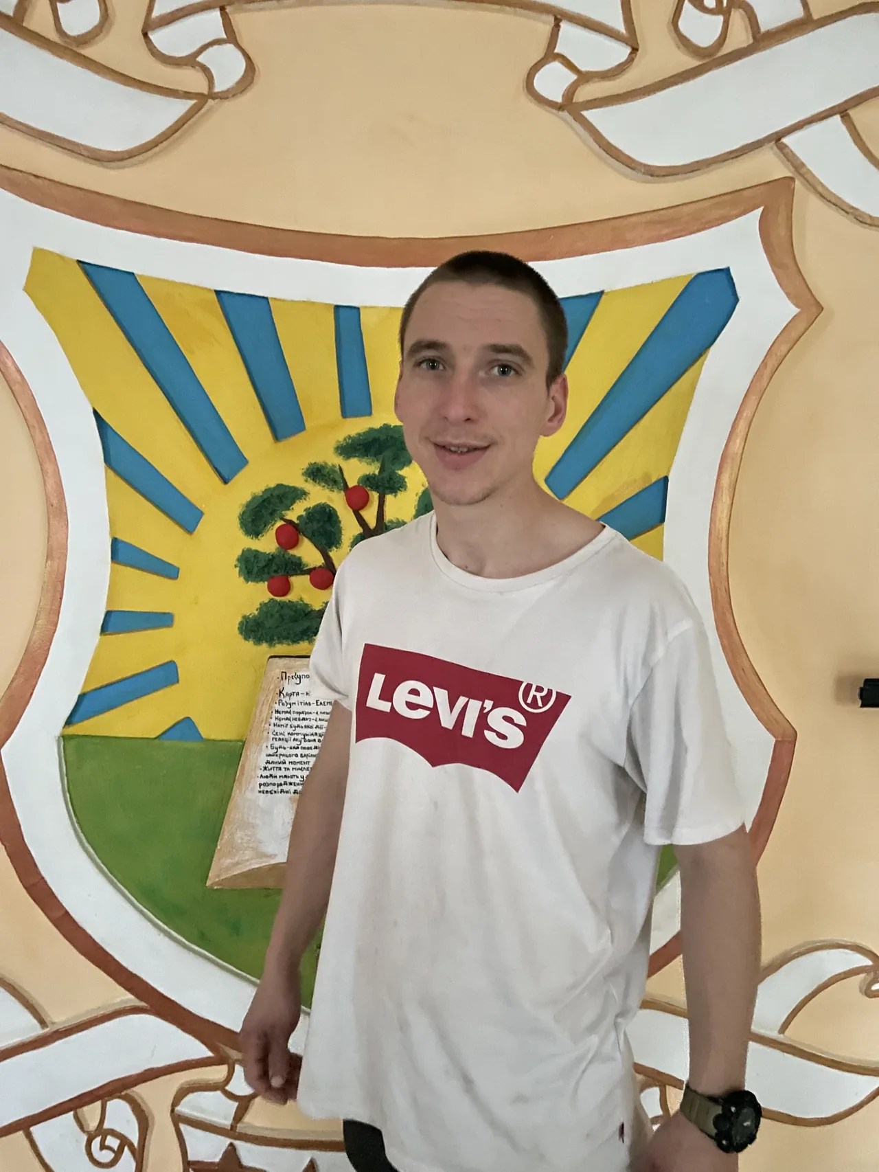 Гена, герой выпуска №7, возле настенной росписи с гербом в центре «Джерело»
